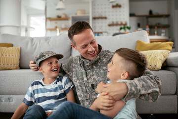 Happy soldier sitting on the floor with his family. Soldier enjoying at home with children.