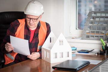 Poster - architectural and construction bureau. a man in a construction helmet studies the construction plan 
