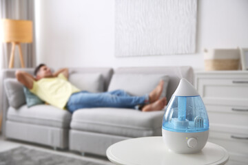 Poster - Modern air humidifier and blurred man resting on background