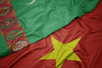 waving colorful flag of vietnam and national flag of turkmenistan.