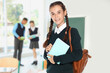 © New Africa - Happy teen girl with backpack in school classroom