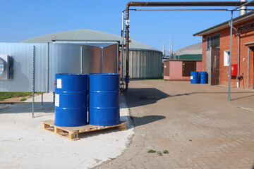 2 big blue barrels stand on a wooden pallet in front of a biogas plant