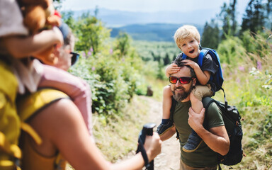 Wall Mural - family with small children hiking outdoors in summer nature.