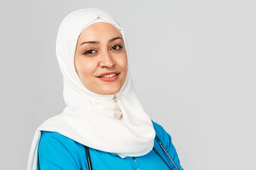 Wall Mural - beautiful modern muslim doctor or nurse in hijab on a gray background. blue uniform.