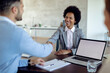 © Drazen - Happy black bank manager handshaking with her client during a meeting in the office.