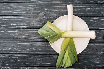 Wall Mural - top view of fresh green leek on plate on wooden surface
