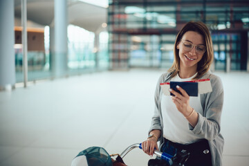 Cheerful female passenger checking boarding pass in airport