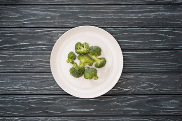 Wall Mural - top view of fresh broccoli on plate on wooden surface