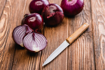 Wall Mural - cut and whole red onion near knife on wooden table