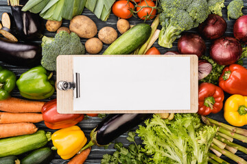 Wall Mural - top view of fresh colorful vegetables around empty clipboard with paper