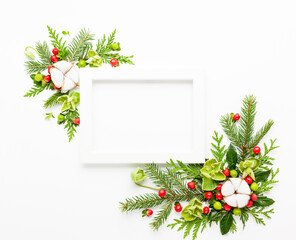 Wall Mural - christmas composition with photo frame, cotton flower, branches of spruce and holly with red berries