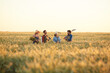 © Seventyfour - Wide angle view at workers holding tools while walking across golden field in sunset light, copy space