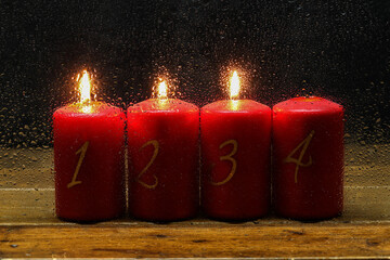 Poster - Closeup advent candles in a row behind a wet glass