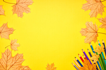 Wall Mural - education and stationery concept. above view for yellow desk. decorated fall leaves and color pencils, markers and other tools. empty space for design