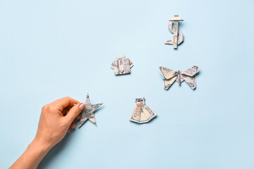 Female hand with different origami figures made from dollar banknotes on color background