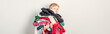 Mommy little helper. Adorable funny child arranging organazing clothing. Kid holding messy stack pile of clothes things. Home chores housework for kids. Web banner header.