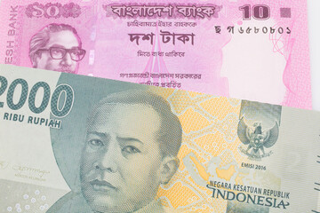 A macro image of a grey two thousand Indonesian rupiah bank note paired up with a pink ten taka bank note from Bangladesh.  Shot close up in macro.