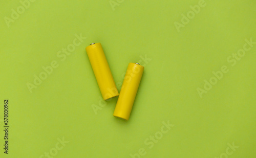 Fotografía Two yellow AA battery on green pastel background. Top view