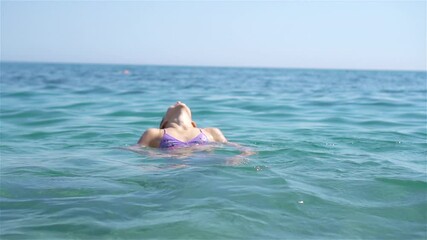 Wall Mural - Happy child splashing in the waves during summer vacation on tropical beach. Girl play at the sea.