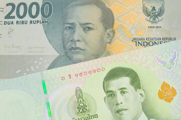 A macro image of a grey two thousand Indonesian rupiah bank note paired up with a green twenty baht bank note from Thailand.  Shot close up in macro.