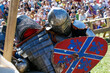 Medieval restorers fight with swords in armor at a knightly tournament