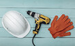 © splitov27 - Old drill screwdriver and protective helmet, gloves on a blue wooden background. Top view