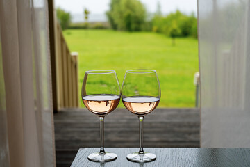 Two glasses with white wine on the table against the background of a green lawn receding into the distance