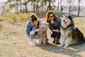 Wall Mural - Women in a spring forest. Girls with cute dogs. Stylish friends walks.