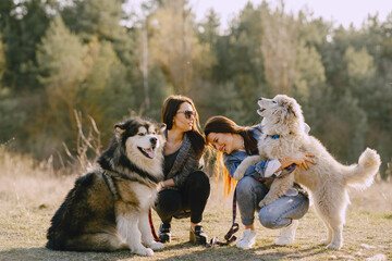 Wall Mural - Women in a spring forest. Girls with cute dogs. Stylish friends walks.