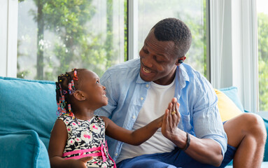 Wall Mural - Cheerful african american father and daughter playing in living room