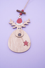 Canvas Print - Vertical shot of a deer-shaped wooden Christmas ornament isolated on a purple background