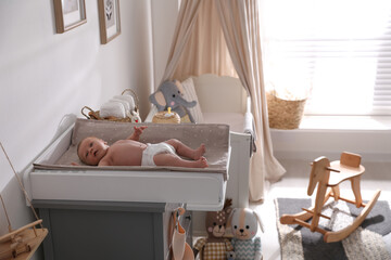 Cute little baby on changing table in room