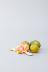 Sticker - Vertical shot of a peeled and whole tangerines on a gray background