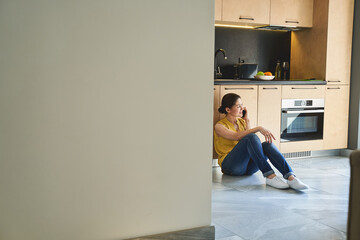 Wall Mural - Woman having a phone conversation in the kitchen