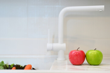 Copy space of apples and vegetables on white kitchen sink.