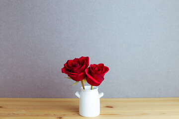 Red rose flowers in vase on wooden table with gray background. floral arrangement, copy space