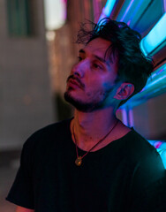 a young handsome man leaning on the neon display at night