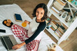 © My Ocean studio - Happy beautiful young brunette woman is working with her laptop while she lay in bed at home. The freelance girl is surfing on internet