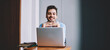 © BullRun - Half length portrait of happy male blogger sitting at desk with laptop device and smiling at camera, skilled man spending time for working remotely with netbook projecting enjoying distance lifestyle
