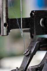 Sewing machine needle with blue thread macro close up shot on the test bench