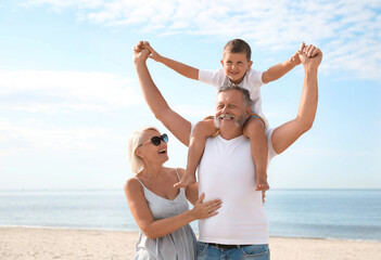 Wall Mural - Little boy and happy grandparents spending time together on sea beach