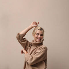 Poster - Happy woman in stylish sweater on beige background