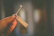 Eine Hand hält einen Schlüssel an dem ein Etikett mit der Aufschrift Zuhause hängt.