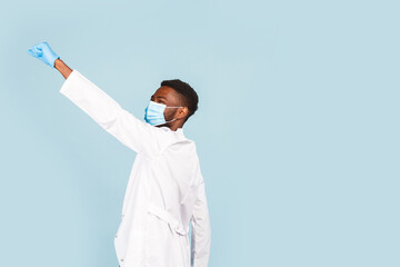 happy African American male doctor with stethoscope wearing mask and gloves on blue background. winner