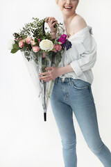 Wall Mural - Cheerful young woman holding umbrella with beautiful bouquet