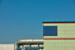 © J.  M√°rquez/Stocksy - Industrial building with pipe against blue sky