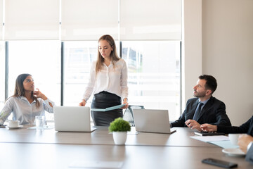 Wall Mural - Businesswoman reading a report to colleagues during meeting