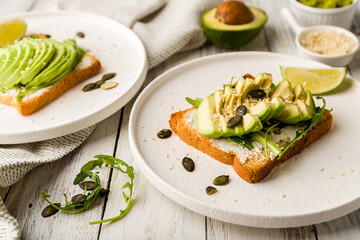 Canvas Print - Toast with avocado, cream cheese,guacamole and arugula on white wooden table