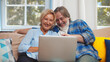 © TommyStockProject - Happy senior couple waving hands doing online video chat with family