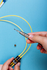 Wall Mural - Women Handholds a screwdriver for tuning the optic attenuator. Selective focus. Blue background